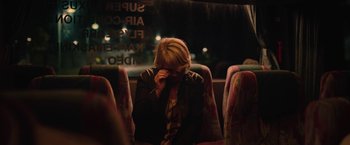 Movie still from “Rose” (2022), directed by Niels Arden Oplev – A woman sitting on a bus with her hand to her face; Medium shot, Over the shoulder angle
