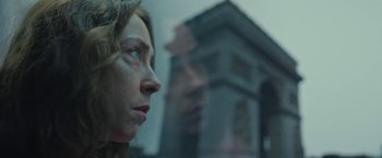Movie still from “Rose” (2022), directed by Niels Arden Oplev – A woman looking out of a window at a building; Close Up shot, Low angle