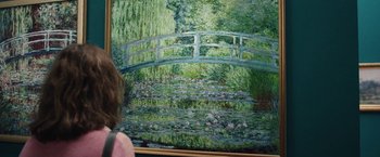 Movie still from “Rose” (2022), directed by Niels Arden Oplev – A person looking at a painting of a bridge; Medium shot, Over the shoulder angle