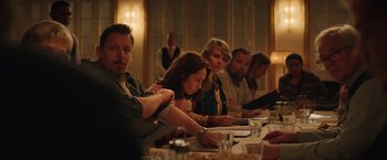 Movie still from “Rose” (2022), directed by Niels Arden Oplev – A group of people sitting at a long dinner table; Medium shot, Over the shoulder angle
