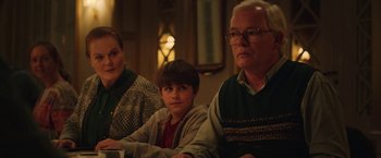 Movie still from “Rose” (2022), directed by Niels Arden Oplev – An older man and a young boy sitting next to each other in front of an older woman; Medium shot, Over the shoulder angle