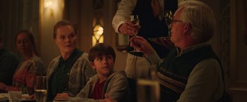 Movie still from “Rose” (2022), directed by Niels Arden Oplev – A person serving a glass of wine to a child; Medium shot, Over the shoulder angle