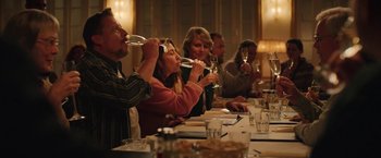 Movie still from “Rose” (2022), directed by Niels Arden Oplev – A group of people sitting at a long table drinking wine; Medium shot, Over the shoulder angle