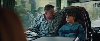 Movie still from “Rose” (2022), directed by Niels Arden Oplev – A man sitting next to a boy on a bus; Medium shot, Over the shoulder angle