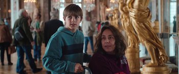 Movie still from “Rose” (2022), directed by Niels Arden Oplev – A woman and a young boy are posing for a picture; Medium shot, Over the shoulder angle