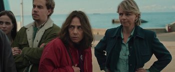 Movie still from “Rose” (2022), directed by Niels Arden Oplev – A group of people standing next to each other on a beach; Medium shot, Over the shoulder angle