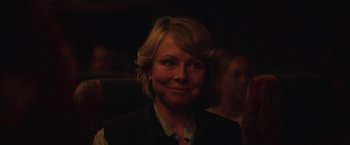 Movie still from “Rose” (2022), directed by Niels Arden Oplev – A woman with blonde hair smiling for the camera; Close Up shot, Over the shoulder angle