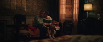 Movie still from “Rose” (2022), directed by Niels Arden Oplev – Two people sitting on a couch in a room; Medium shot, High angle