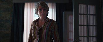Movie still from “Rose” (2022), directed by Niels Arden Oplev – A woman standing in front of a window in a room; Medium shot, Low angle