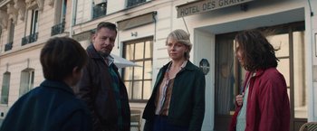 Movie still from “Rose” (2022), directed by Niels Arden Oplev – A man and a woman standing in front of a building; Medium shot, Low angle