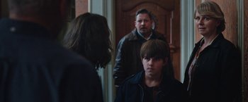 Movie still from “Rose” (2022), directed by Niels Arden Oplev – A group of people standing in front of a wooden door; Medium shot, Over the shoulder angle