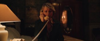 Movie still from “Rose” (2022), directed by Niels Arden Oplev – A woman talking on a phone while wearing a jacket; Medium shot, High angle