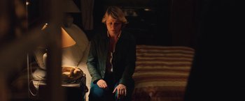 Movie still from “Rose” (2022), directed by Niels Arden Oplev – A woman sitting on a bed in a dark room; Medium shot, High angle