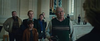 Movie still from “Rose” (2022), directed by Niels Arden Oplev – A group of people standing in a room; Medium shot, Low angle