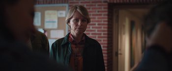 Movie still from “Rose” (2022), directed by Niels Arden Oplev – A woman standing in front of a brick wall in a room; Close Up shot, Over the shoulder angle