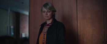 Movie still from “Rose” (2022), directed by Niels Arden Oplev – A woman standing in front of a wooden wall; Medium shot, Over the shoulder angle