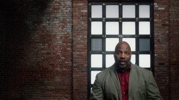 Movie still from “13th” (2016), directed by Ava DuVernay – A man standing in front of a brick wall; Medium shot, Low angle