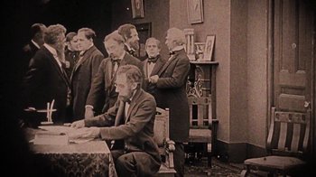 Movie still from “13th” (2016), directed by Ava DuVernay – A group of men standing around a table; Wide shot, High angle
