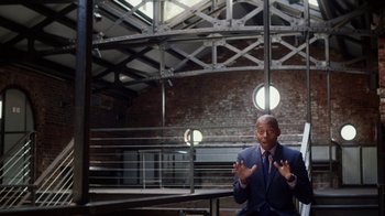 Movie still from “13th” (2016), directed by Ava DuVernay – A man in a suit and tie standing in front of a building; Medium shot, Low angle