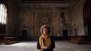 Movie still from “13th” (2016), directed by Ava DuVernay – An older woman wearing a yellow scarf in an old building; Medium shot, Low angle