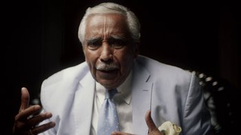 Movie still from “13th” (2016), directed by Ava DuVernay – An older man wearing a white suit and a blue tie; Close Up shot, Over the shoulder angle