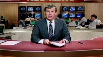 Movie still from “13th” (2016), directed by Ava DuVernay – A man sitting at a news desk in front of a television; Medium shot, Low angle