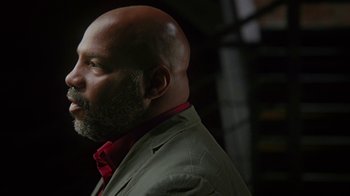 Movie still from “13th” (2016), directed by Ava DuVernay – A bald man with a beard and a red tie; Close Up shot, Low angle