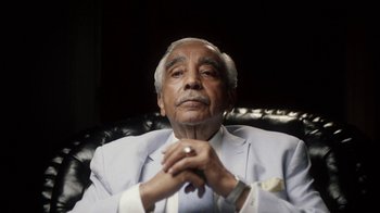 Movie still from “13th” (2016), directed by Ava DuVernay – An older man in a white suit sitting in a chair; Close Up shot, Low angle