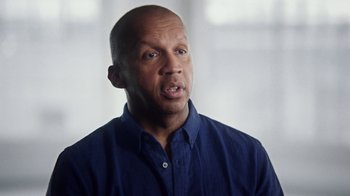 Movie still from “13th” (2016), directed by Ava DuVernay – A bald man in a blue shirt is looking at the camera; Close Up shot, Low angle
