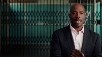 Movie still from “13th” (2016), directed by Ava DuVernay – A man wearing a suit and tie standing in front of a building; Close Up shot, Over the shoulder angle