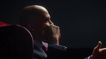 Movie still from “13th” (2016), directed by Ava DuVernay – A bald man in a suit and red tie is sitting in a chair; Close Up shot, Low angle