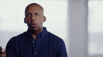 Movie still from “13th” (2016), directed by Ava DuVernay – A bald man in a blue shirt is making a funny face; Close Up shot, Low angle