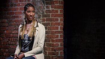 Movie still from “13th” (2016), directed by Ava DuVernay – A woman sitting in front of a brick wall; Medium shot, Low angle
