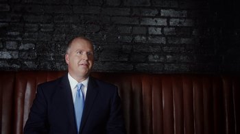 Movie still from “13th” (2016), directed by Ava DuVernay – A man in a suit sitting in front of a brick wall; Close Up shot, Low angle