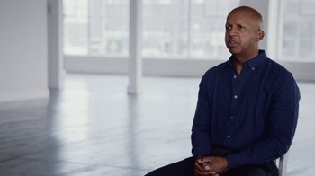Movie still from “13th” (2016), directed by Ava DuVernay – A man sitting on the ground in a room; Medium shot, Low angle