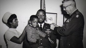 Movie still from “13th” (2016), directed by Ava DuVernay – An old black and white photo of a man holding a young boy; Medium shot, Low angle