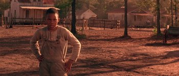 Movie still from “Rosewood” (1997), directed by John Singleton – A young boy in overalls standing in a dirt field; Medium shot, Low angle