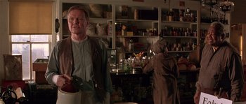 Movie still from “Rosewood” (1997), directed by John Singleton – A man standing in front of a woman in a kitchen; Medium shot, Over the shoulder angle