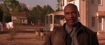 Movie still from “Rosewood” (1997), directed by John Singleton – A man standing in front of an old house; Close Up shot, Low angle