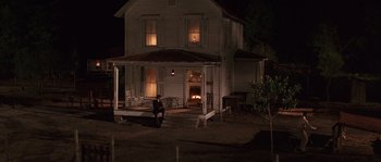 Movie still from “Rosewood” (1997), directed by John Singleton – A person sitting on a porch in front of a house at night; Wide shot, High angle