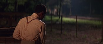 Movie still from “Rosewood” (1997), directed by John Singleton – A man standing in a field at night; Medium shot, Over the shoulder angle