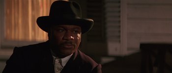 Movie still from “Rosewood” (1997), directed by John Singleton – A man wearing a suit and a hat is looking at the camera; Close Up shot, Low angle