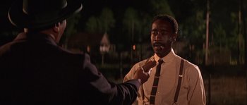 Movie still from “Rosewood” (1997), directed by John Singleton – A man in a suit and tie is holding his hand out to another man in a suit and tie; Medium shot, Over the shoulder angle