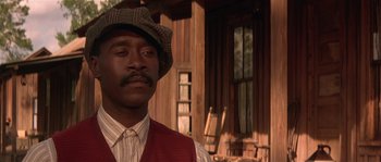 Movie still from “Rosewood” (1997), directed by John Singleton – A man wearing a red vest and a brown hat; Close Up shot, Low angle