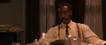 Movie still from “Rosewood” (1997), directed by John Singleton – A man sitting at a table with a candle in front of him; Close Up shot, Over the shoulder angle
