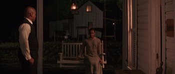 A woman sitting on a porch swing at night