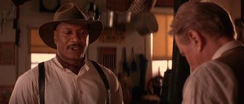 Movie still from “Rosewood” (1997), directed by John Singleton – A man wearing a cowboy hat and suspenders in a kitchen; Close Up shot, Low angle