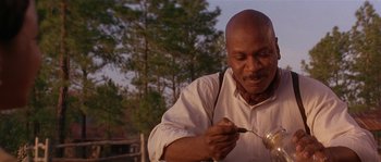 Movie still from “Rosewood” (1997), directed by John Singleton – An older man holding a spoon in his hand; Close Up shot, Low angle
