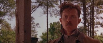 Movie still from “Rosewood” (1997), directed by John Singleton – A person wearing a jacket near a tree; Close Up shot, Low angle