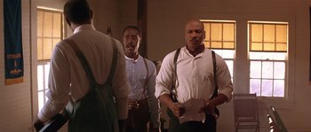 Movie still from “Rosewood” (1997), directed by John Singleton – A couple of men standing next to each other in a room; Medium shot, Low angle